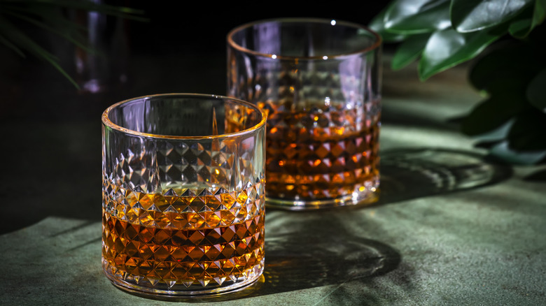 2 rock glasses with amber colored whiskies on a dark background