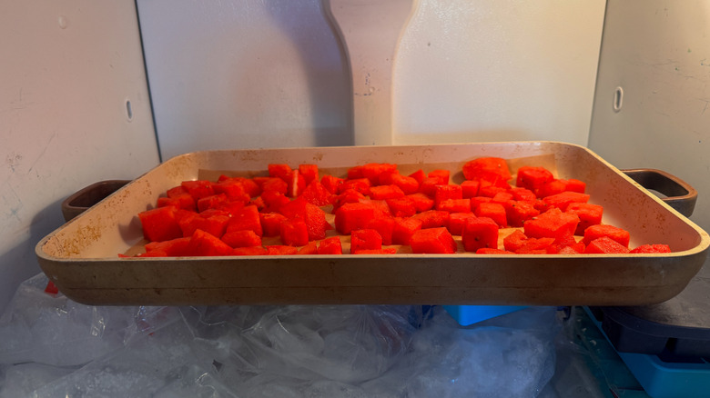 sheet pan full of watermelon chunks in freezer