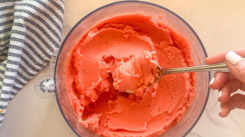 spoon lifting watermelon sorbet out of food processor
