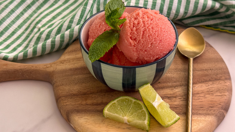 Bowl of watermelon sorbet with mint and lime wedges