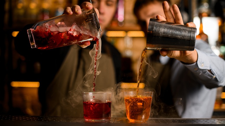 Bartenders pouring cocktails from shakers
