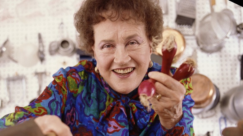 Julia Child in her kitchen holidng some red onions