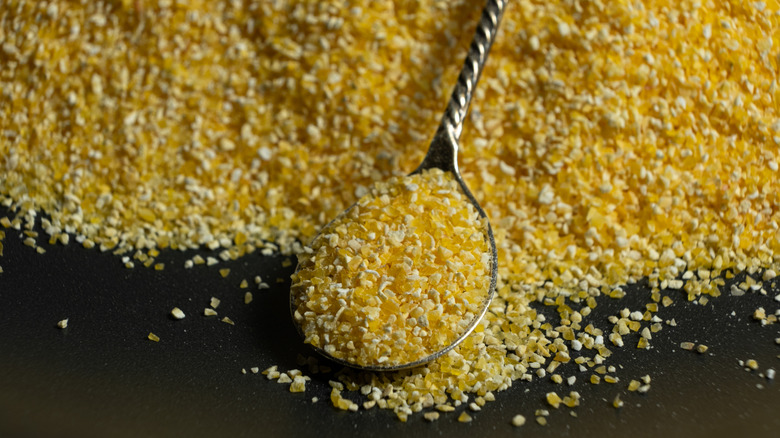 A spoonful of raw cornmeal with a pile of cornmeal behind it