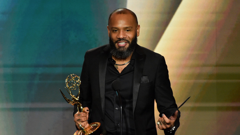Justin Sutherland speaking while holding Emmy