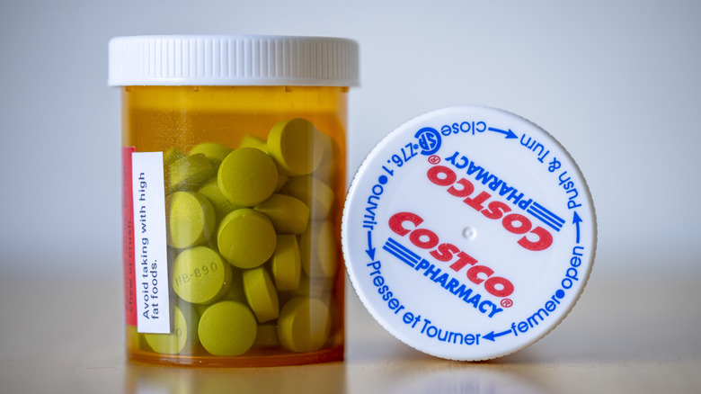 An orange Costco prescription bottle filled with green-ish pills