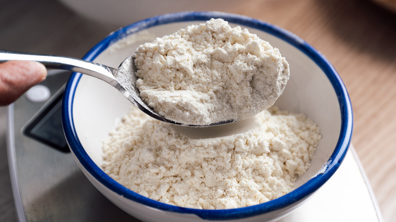 View of measuring Bisquick mix on a baking scale with a spoon.