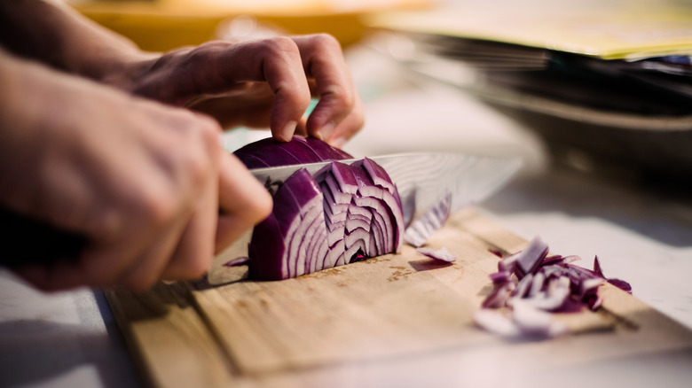 A person cutting red onions