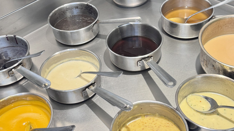 Aluminum sauce pans with sauces and spoons