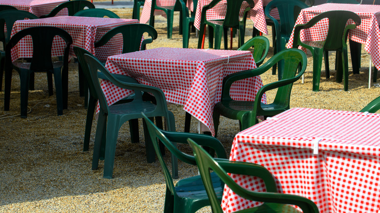 group of outdoor tables with plastic tablecloths clipped to them