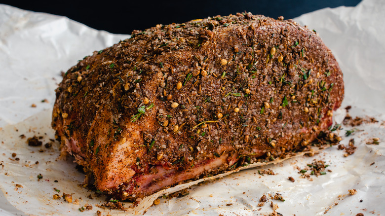 An uncooked prime rib roast covered in a coating of seasonings