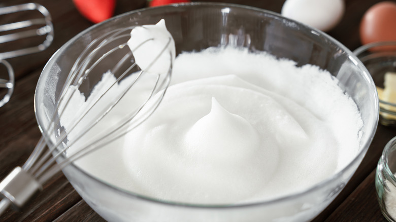 Bowl of whipped egg whites with a whisk resting on the edge
