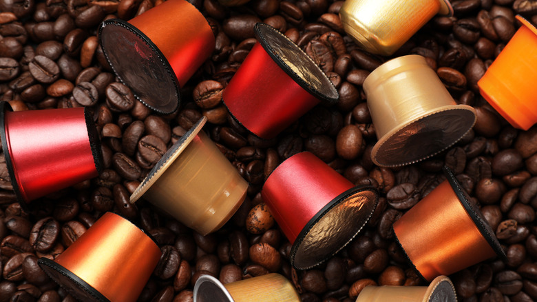 a stack of multi color coffee pods on top of coffee beans