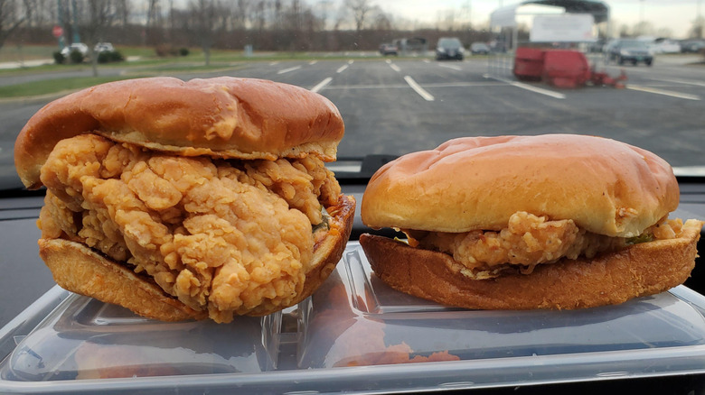 KFC and Popeyes classic chicken sandwiches on a car dashboard