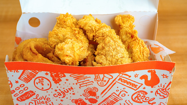 A box of Popeye's Chicken in their signature box sitting on a wooden table