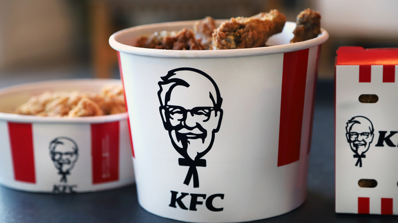 A bucket of KFC chicken next to a KFC box and smaller bucket