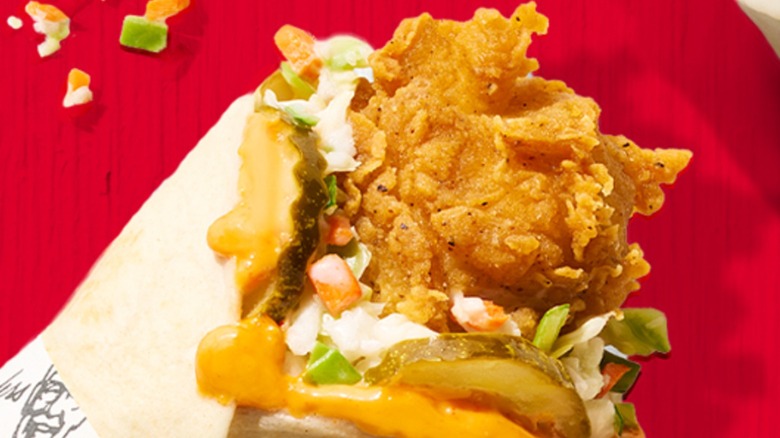 Close up of a KFC fried chicken wrap on a red background