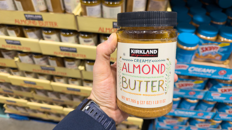 Member holding jar of Kirkland Creamy Almond Butter