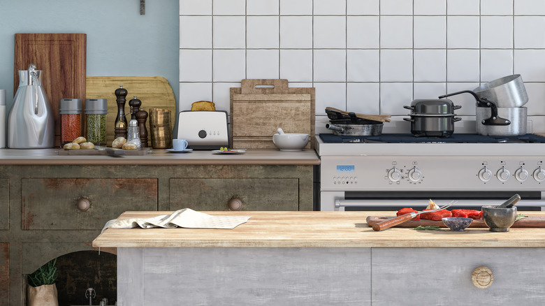 A kitchen with a wooden countertop, steel stove and various pots and pans