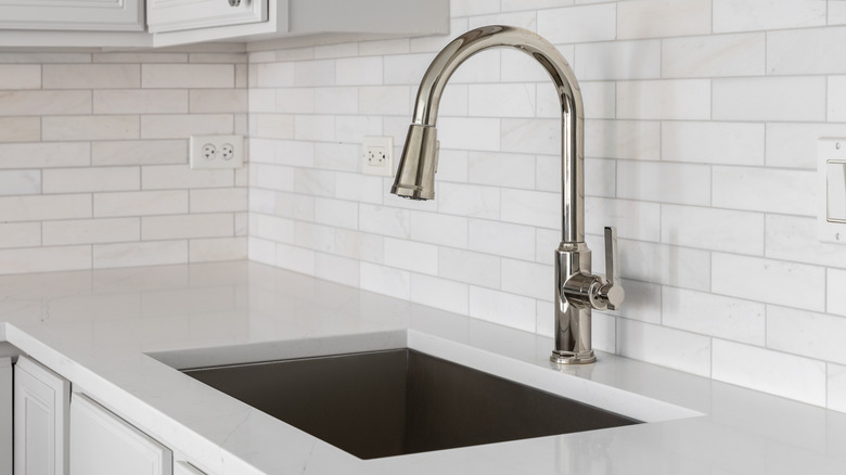 Plain white tile backsplash behind kitchen sink