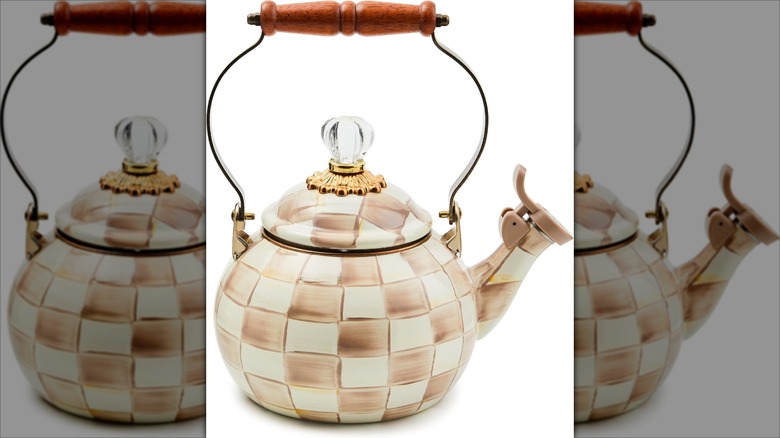 Checkered enamel teapot with wooden handle on white background