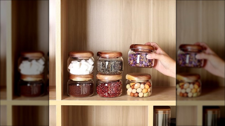 Six filled spice jars on wooden shelf