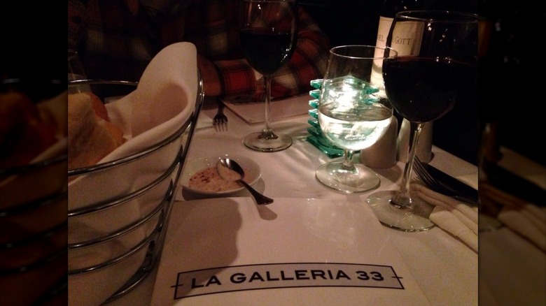 La Galleria 33's menu on a white linen table beside a basket of bread and wine glasses