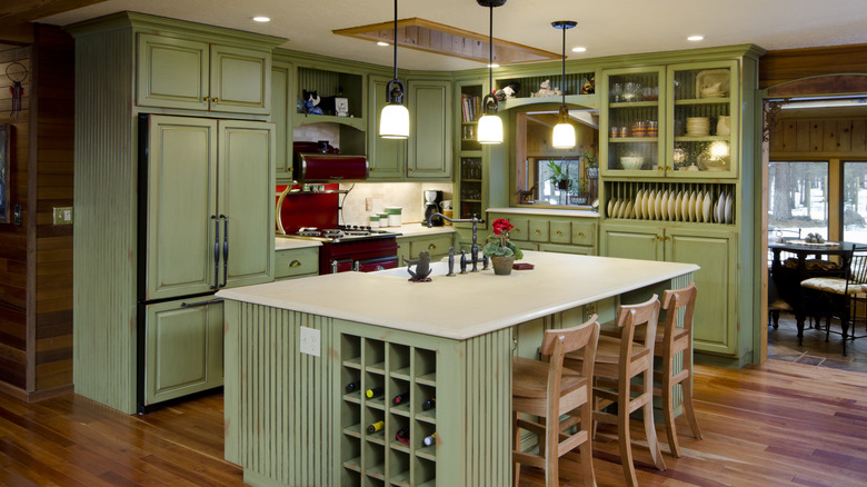 View of light green kitchen from wooden counter