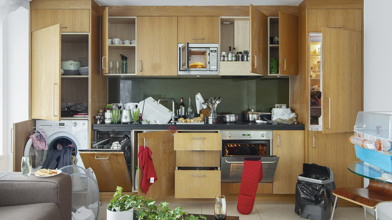 Cluttered kitchen layout with open sink, dishwasher and washing machine