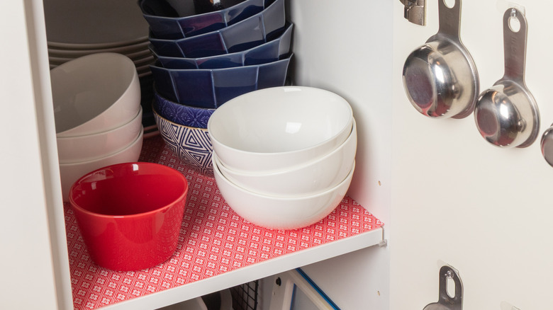kitchen shelf lined with paper with bowls