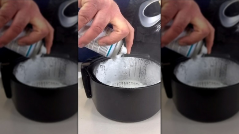 Spraying cleaning foam into air fryer basket