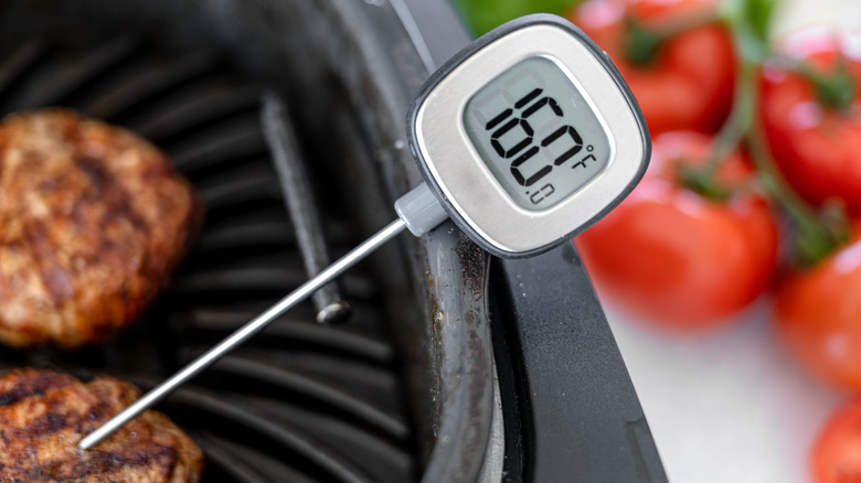 Probe thermometer checking temperature of burger
