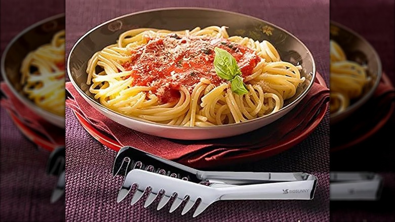 A pair of Msy BigSunny kitchen pasta tongs by a bowl of spaghetti