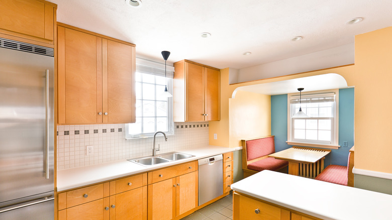 A kitchen with white countertops of light wooden cabinets
