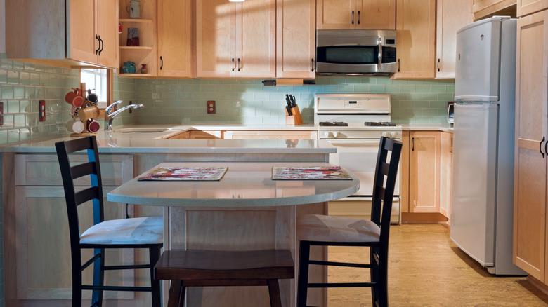 A kitchen with a peninsula, placemats, and chairs
