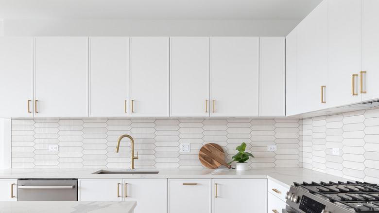 White kitchen cabinets and a gold kitchen tap