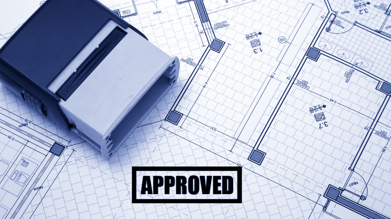 architectural drawings with a pre-inked stamp on top, and a stamp reading "Approved" on the documents themselves