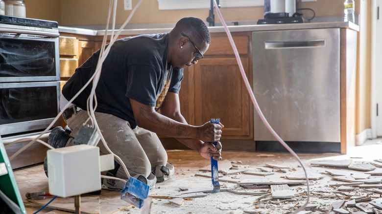 tradesman removing tiles from a kitchen floor by hand