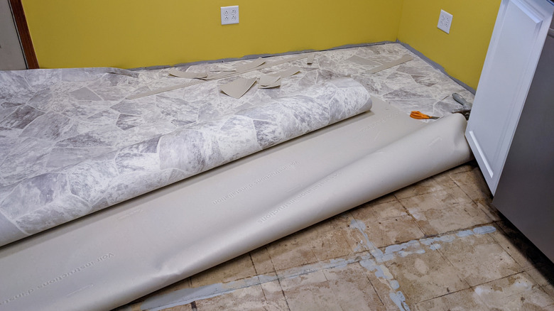 new vinyl flooring being installed over top of sketchy-looking older tiles in an older home