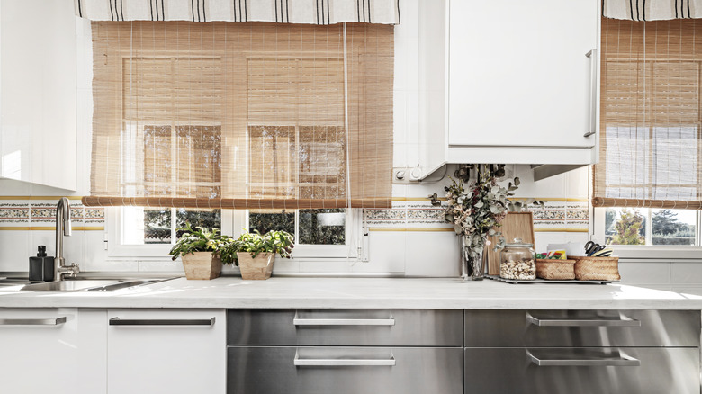 Bamboo shades above a white and metallic kitchen