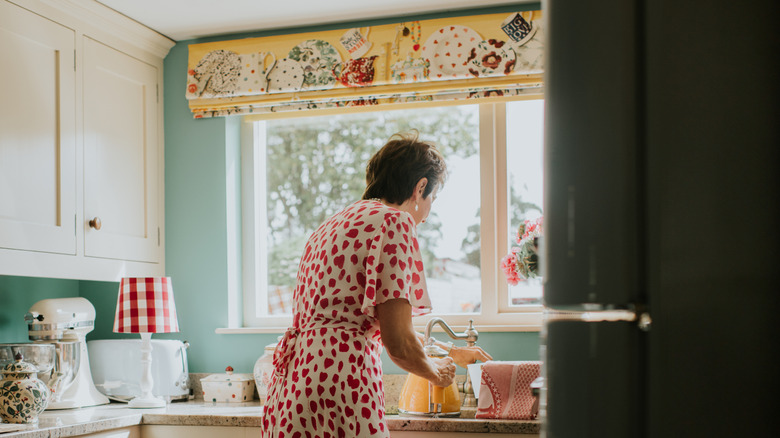 A woman filling a kettle under a yellow mounted blind