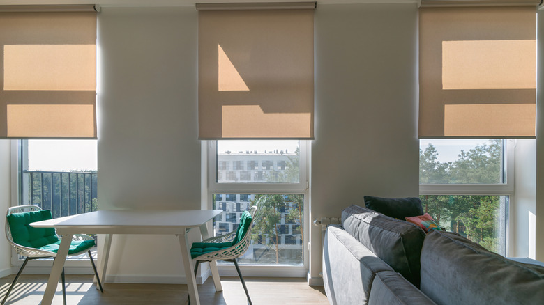 Three tan-colored roller shades in an open-plan space