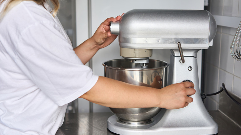 person setting up a stand mixer on a countertop