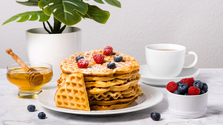 round waffles topped with berries, sugar, and honey