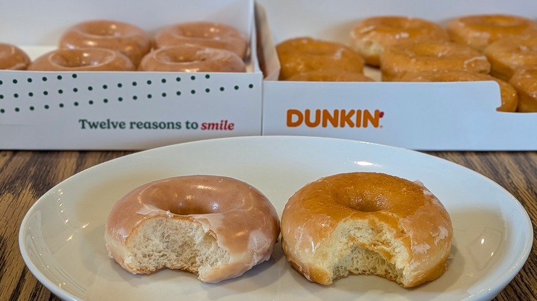 Krispy Kreme and Dunkin' donuts with bites taken out in front of two open donut boxes