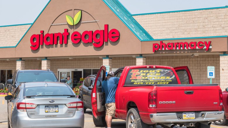 The exterior of a Giant Eagle pharmacy during daytime, with several vehicles park in front of it.