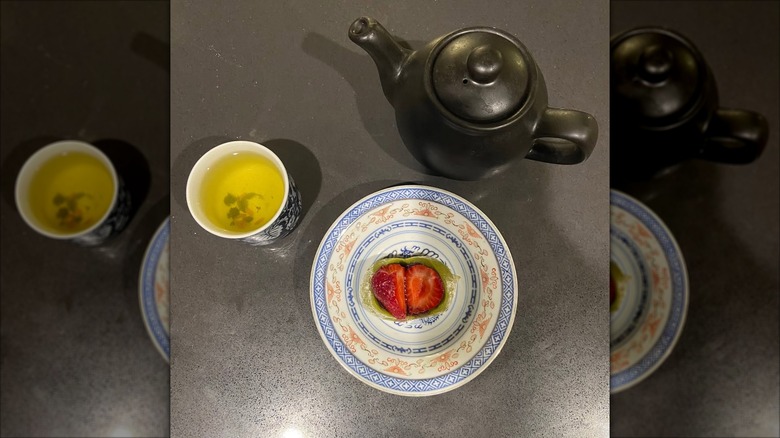 Mochi stuffed with strawberry's, a teapot, and a cup of tea