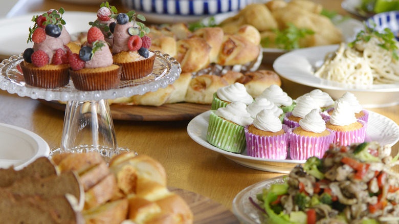 Different dishes of breads, salad, cupcakes and more on a buffet table