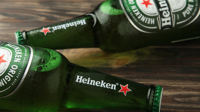 Two bottles of Heineken laid down in opposite directions on a wooden surface