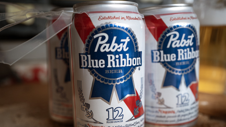 A close shot of a pack of six Pabst Blue Ribbon cans, with two having been taken