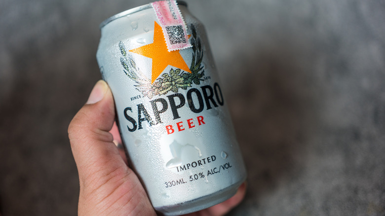 A can of Sapporo beer held in someone's hand and shown to camera